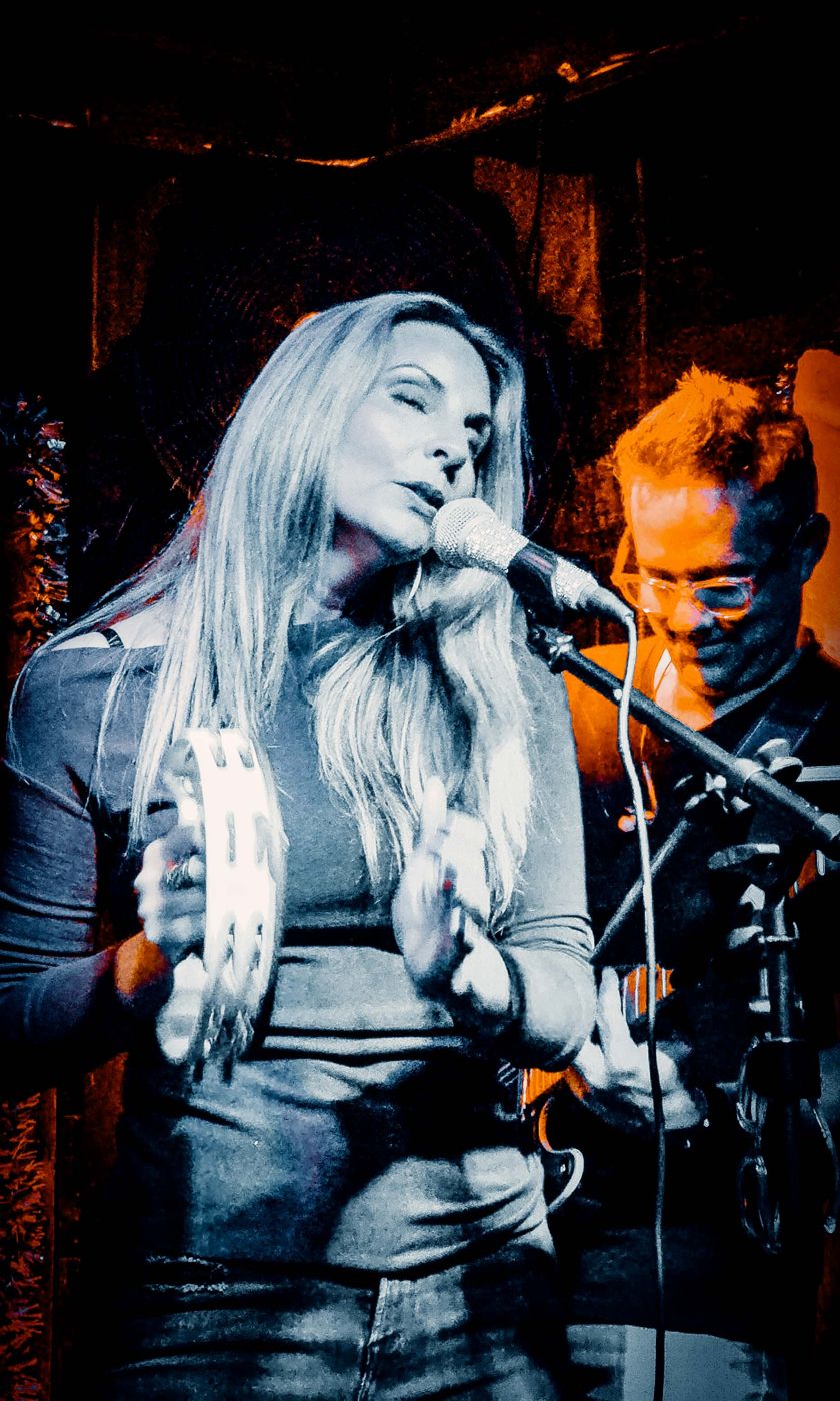 Singer with a tambourine under warm stage light