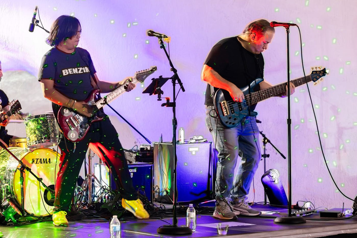 Two guitarists side by side under purple light