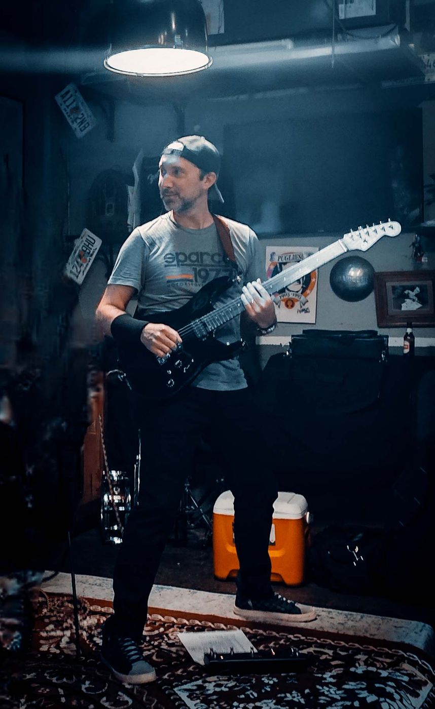 Guitarist in the rug room under a hanging lamp