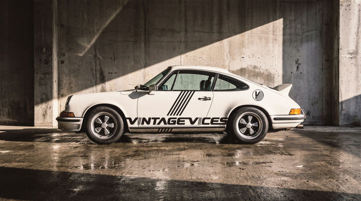 White classic car in Vintage Vices livery parked in a concrete hall