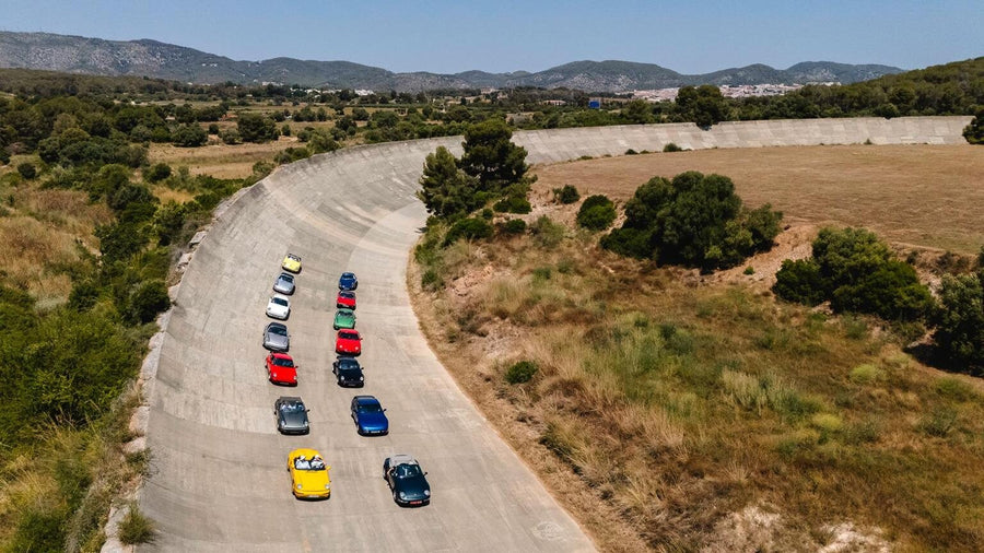 A line of classic cars on the banked oval at Terramar