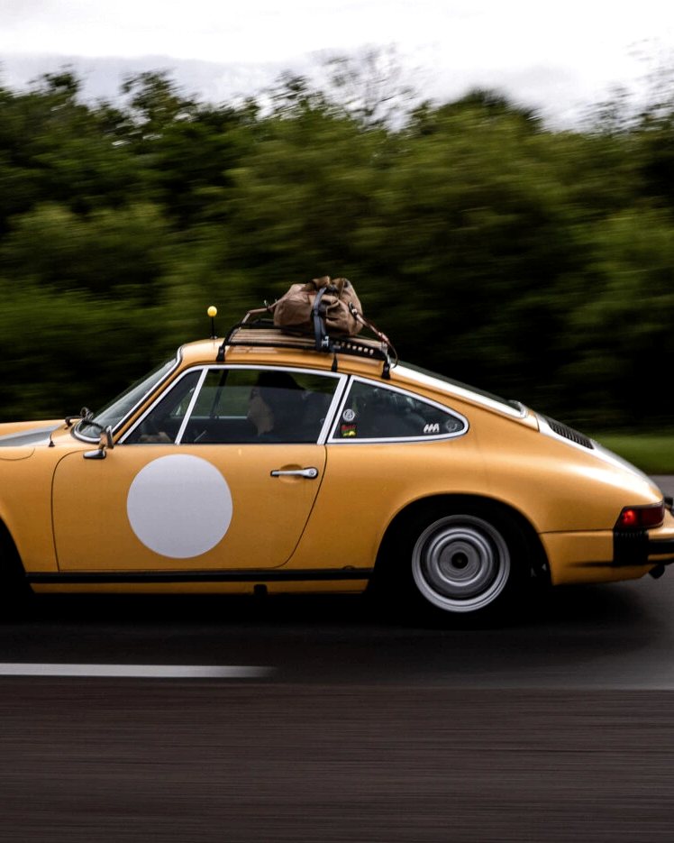 Yellow classic with a roof rack on the road
