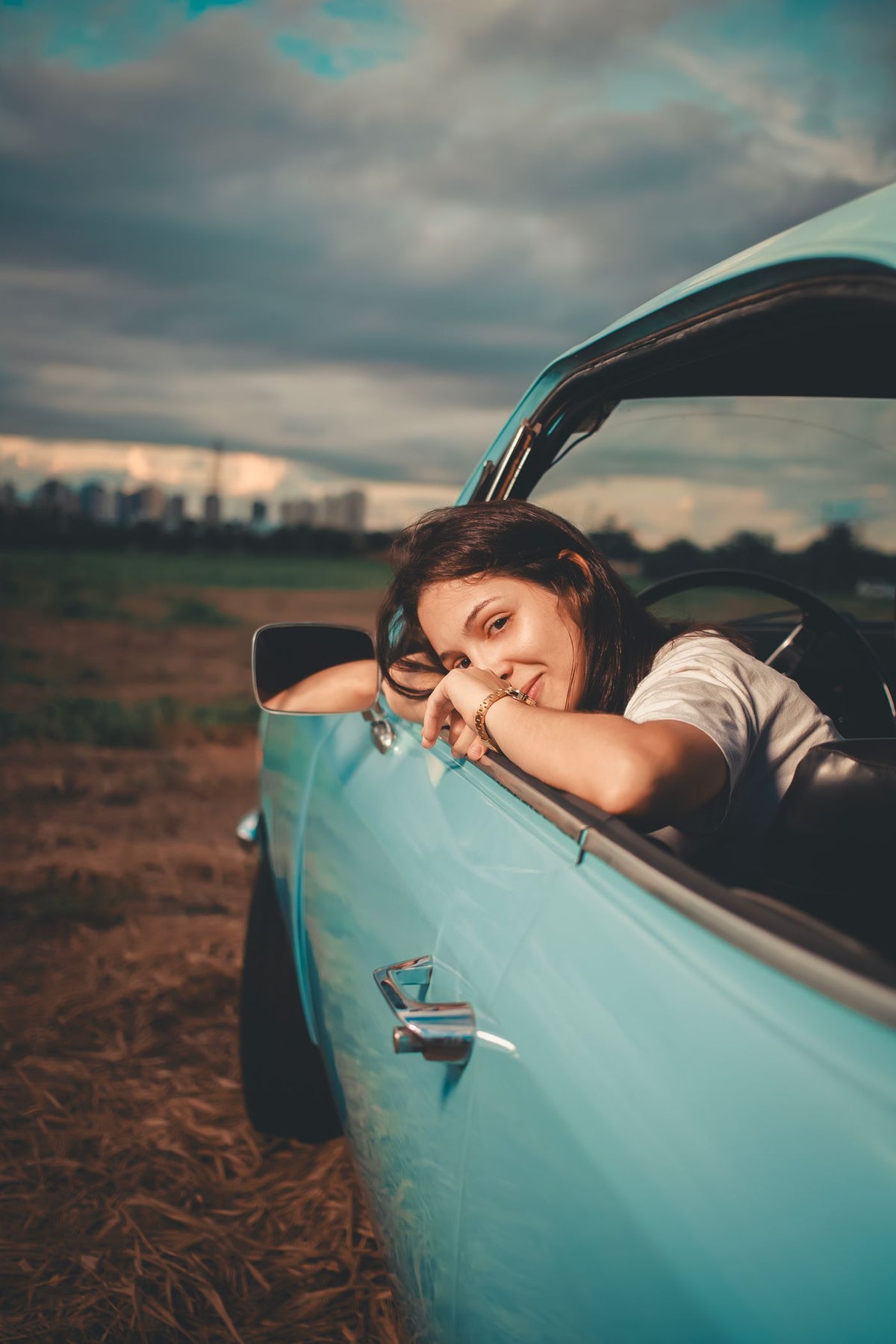 A smiling woman leaning out the window of a vintage car